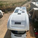 Camping-car blanc avec panneaux solaires sur le toit.