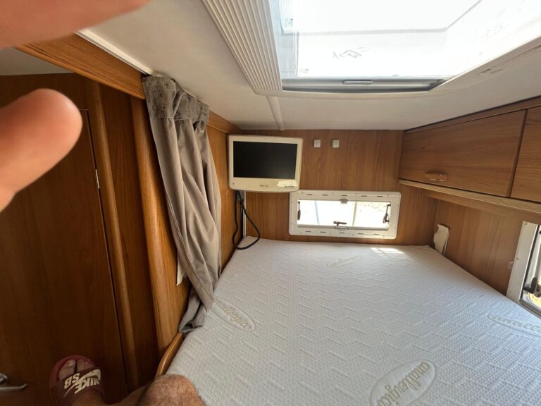 Intérieur de caravane avec lit et télévision.