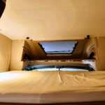 Intérieur d'un camping-car avec lit et fenêtre.