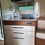 Cuisine compacte en bois et métal dans un camping-car.