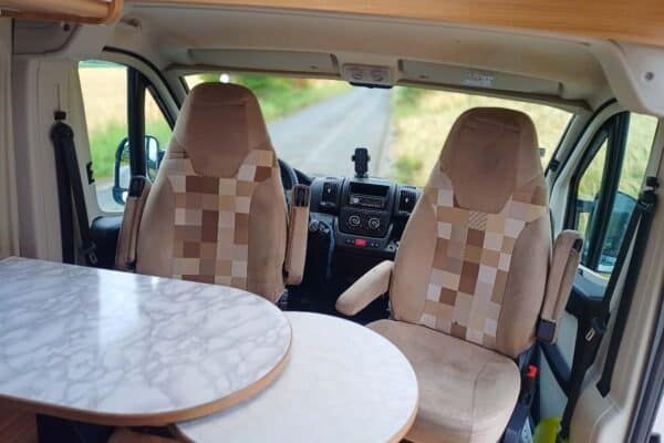 Innenansicht eines modernen Wohnmobil mit Sitzen und Tisch.