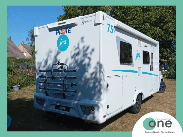 Camping-car blanc stationné dans un jardin.