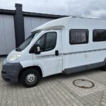 Camping-car stationné devant un bâtiment industriel.