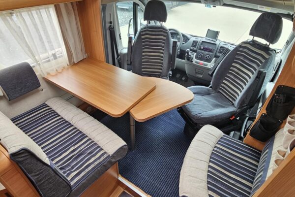 Komfortabler Innenraum von Wohnmobil mit Sitzen und Tisch.