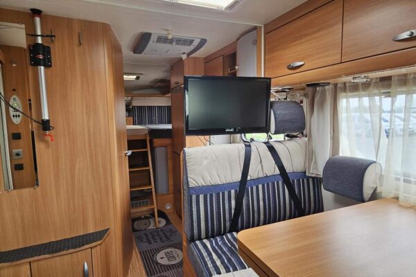 Innenseite von Wohnmobil mit Tisch und Fernseher.