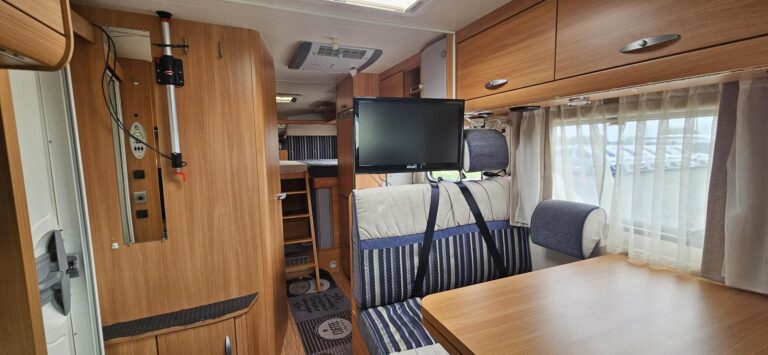 Intérieur de camping-car avec table et télé.