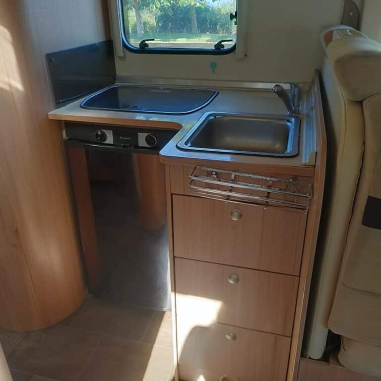 Petite cuisine de camping-car éclairée par le soleil.
