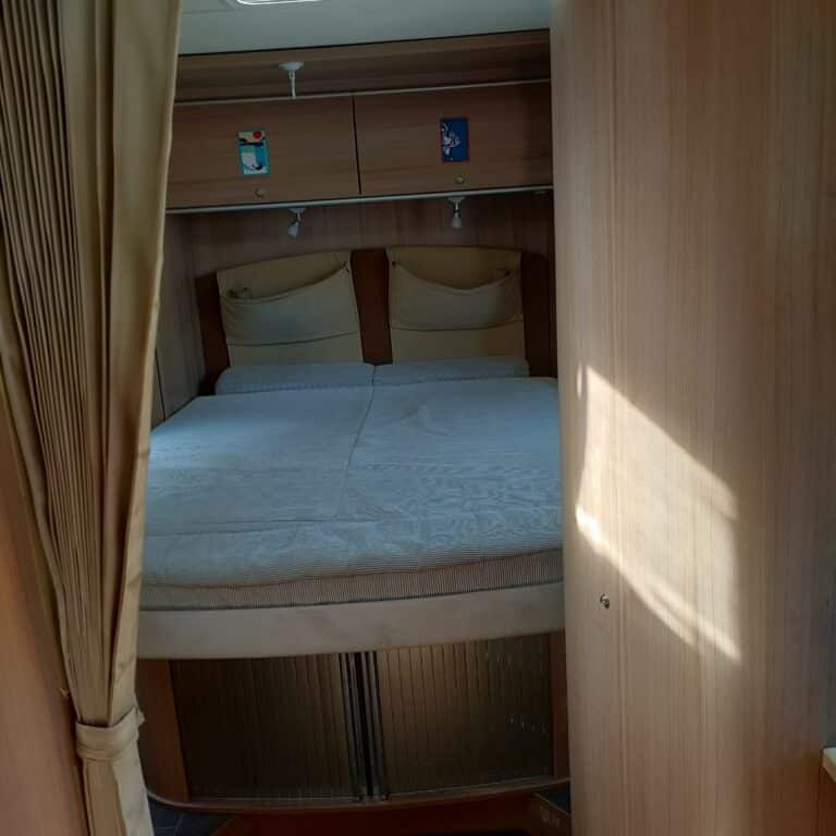 Lit double dans une caravane en bois clair.