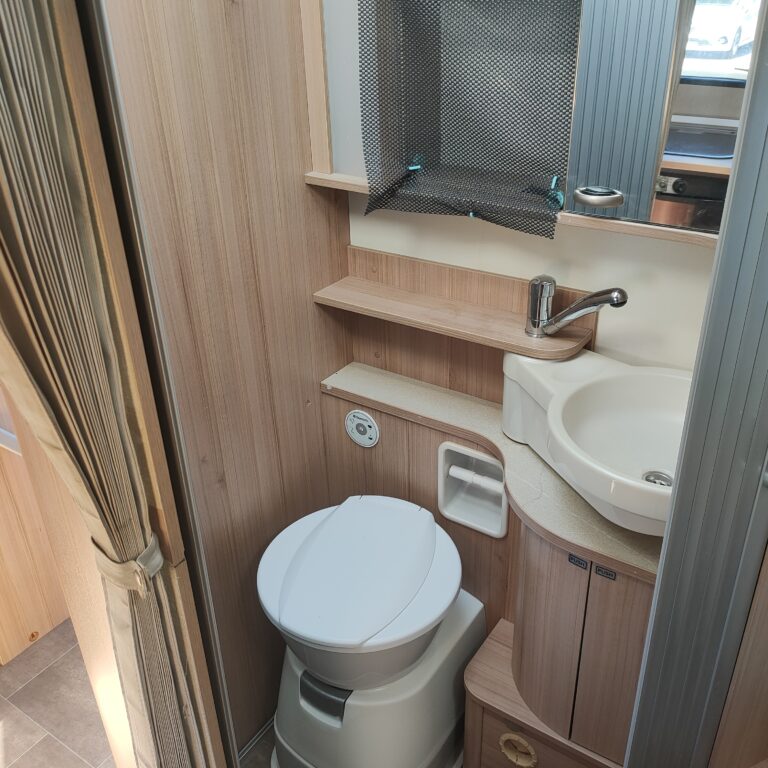 Salle de bain compacte en bois clair, lavabo et toilettes.