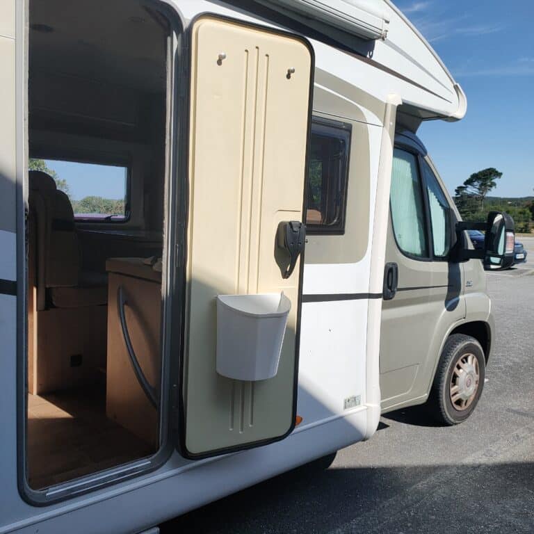 Porte ouverte d'un camping-car dans un parking.