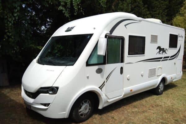 Camping-car blanc stationné sur l'herbe