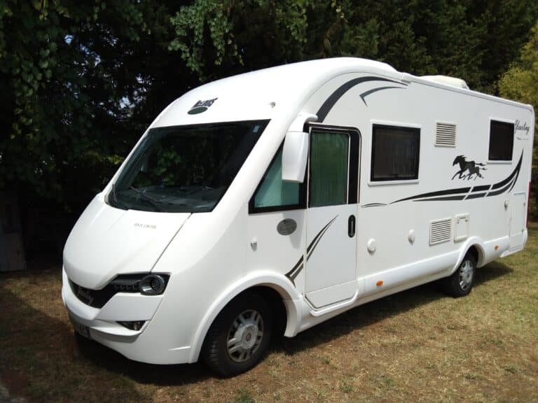 Camping-car blanc stationné sur l'herbe
