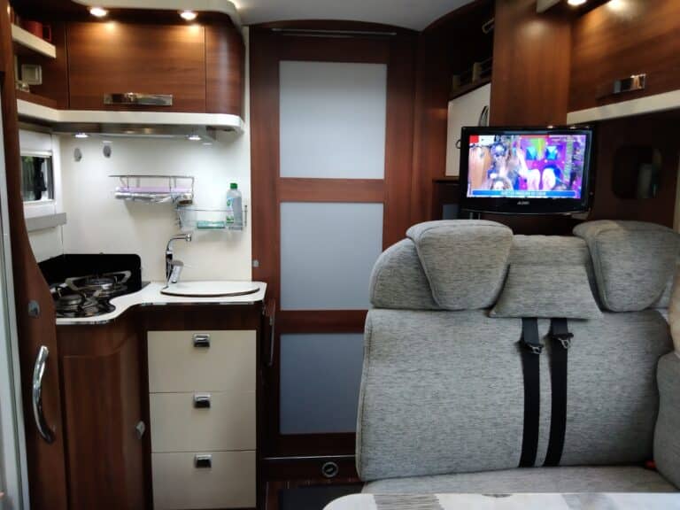 Intérieur d'un camping-car avec cuisine et télévision.