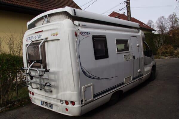Weißer Wohnmobil, der in einer Einfahrt geparkt ist.