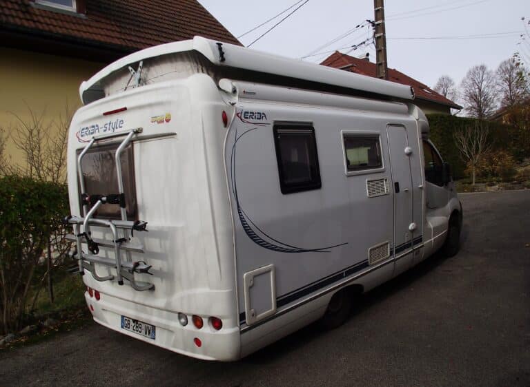Camping-car blanc stationné dans une allée.