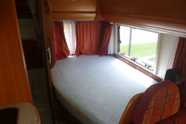 Bett in einem Wohnmobil mit geschlossenen roten Vorhängen