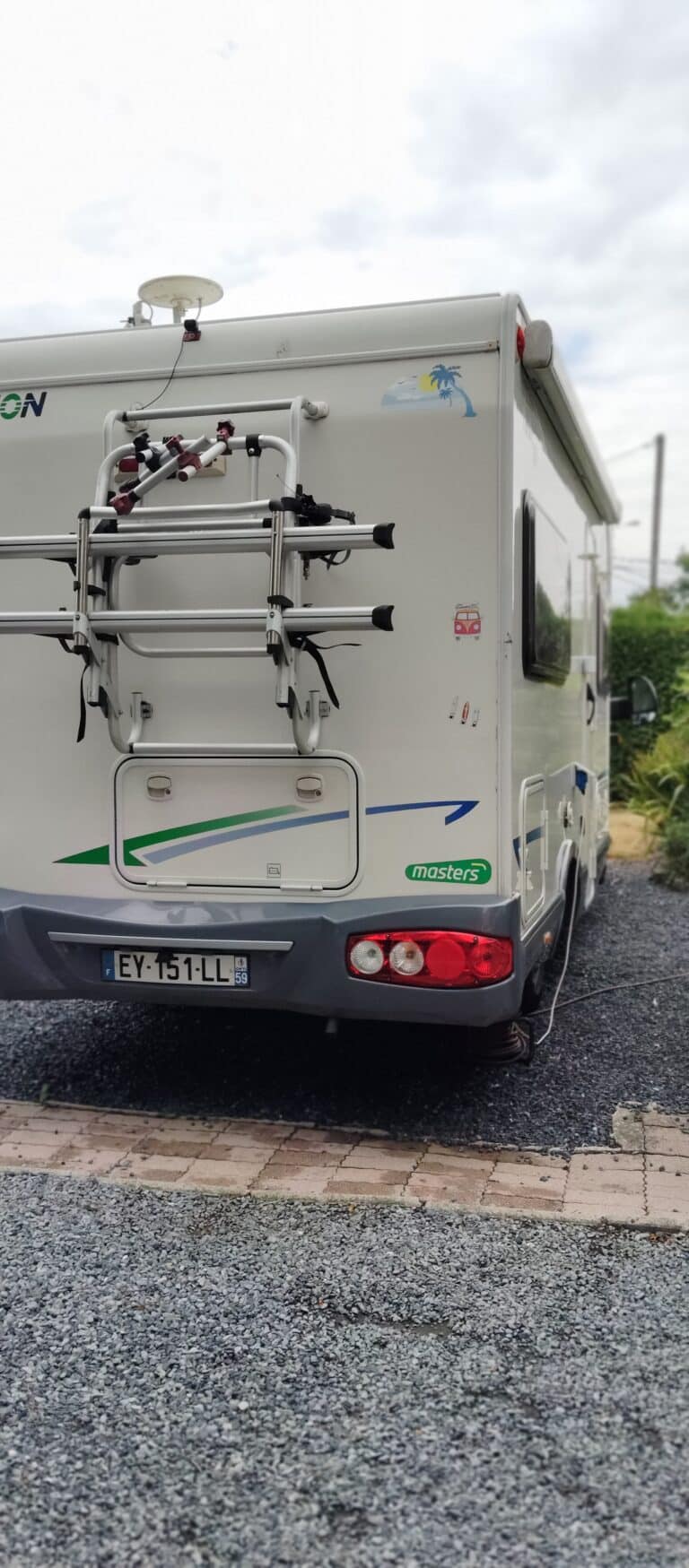 Arrière d'un camping-car blanc avec porte-vélos.