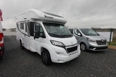 Camping-car blanc stationné à côté d'un van gris.
