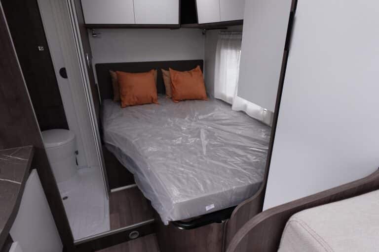 Lit double avec oreillers orange dans caravane