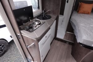 Intérieur camping-car: cuisine, lit et salle de bain.