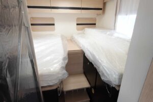 Lits jumeaux sous plastique dans un camping-car.