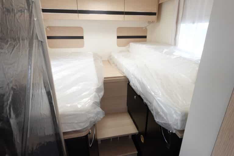 Lits jumeaux sous plastique dans un camping-car.