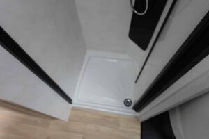 Douche moderne avec parois blanches et sol en bois.