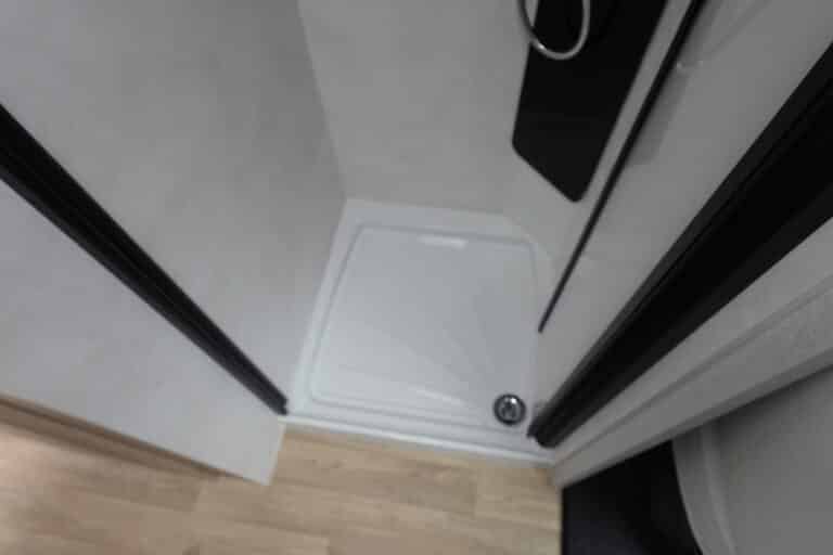 Douche moderne avec parois blanches et sol en bois.