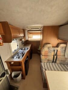 Intérieur de caravane avec cuisine et banquette.