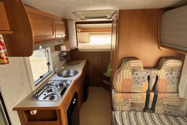 Intérieur de caravane avec cuisine et banquette.