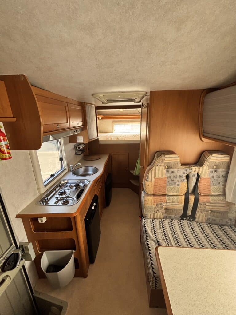 Intérieur de caravane avec cuisine et banquette.
