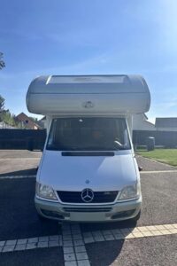 Camping-car Mercedes stationné sur un parking.