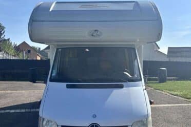 Camping-car Mercedes stationné sur un parking.