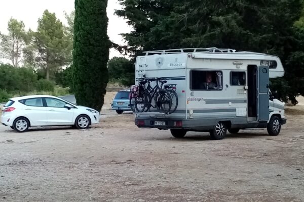 Wohnmobil mit Fahrrädern auf einem bewaldeten Parkplatz.