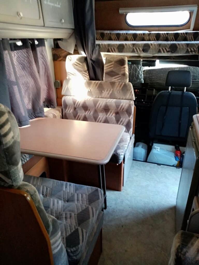 Intérieur de camping-car avec table et sièges rembourrés.
