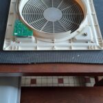 Ventilateur démonté avec carte électronique sur une table.