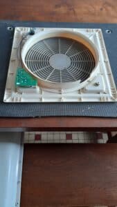 Ventilateur démonté avec carte électronique sur une table.