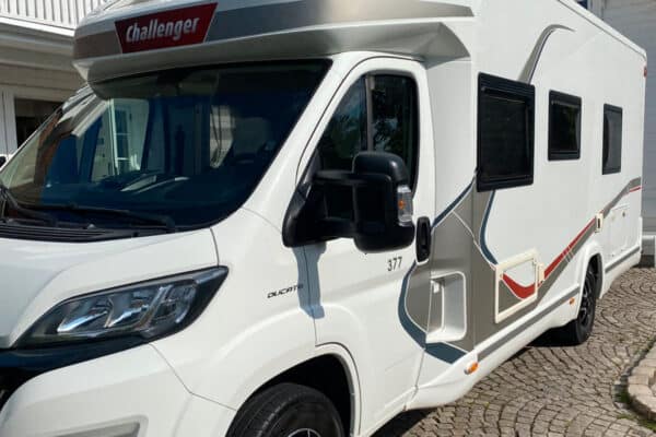 Camping-car blanc stationné devant une maison