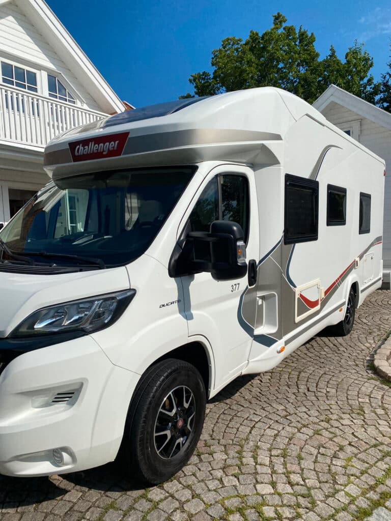 Camping-car blanc stationné devant une maison