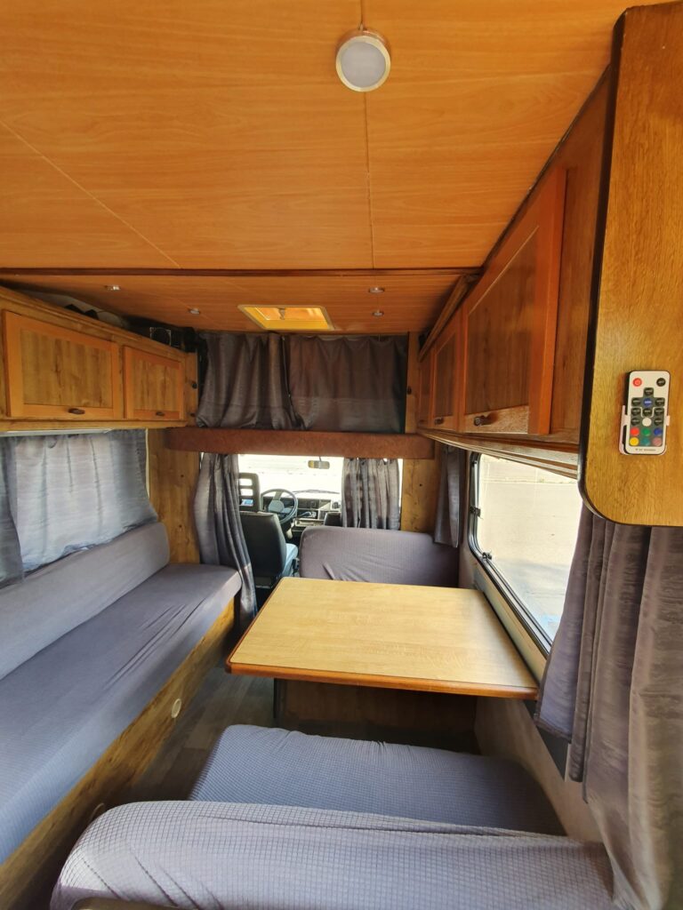 Intérieur d'un camping-car avec banquettes et table.