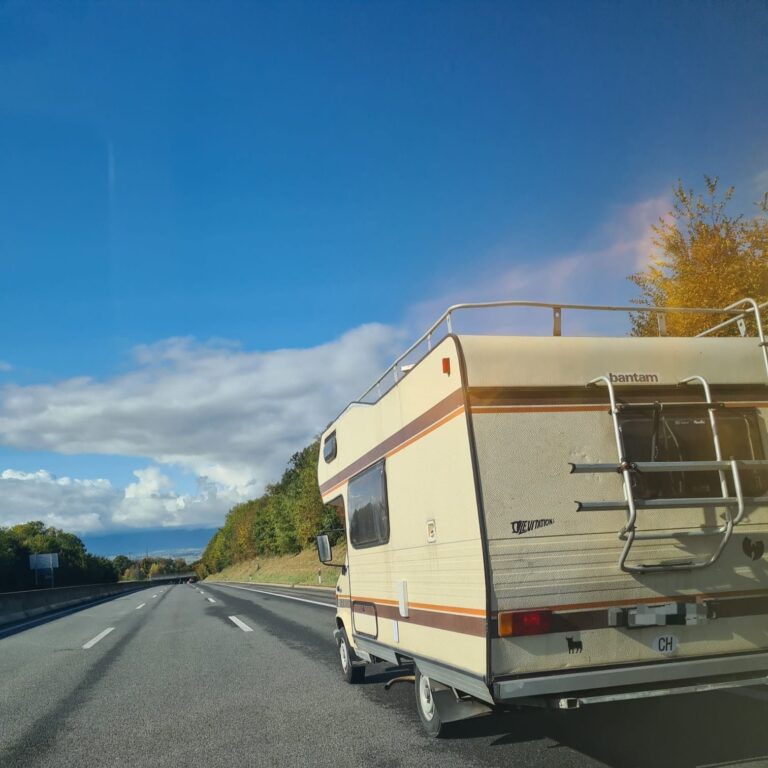 Camping-car roulant sur autoroute sous ciel bleu.
