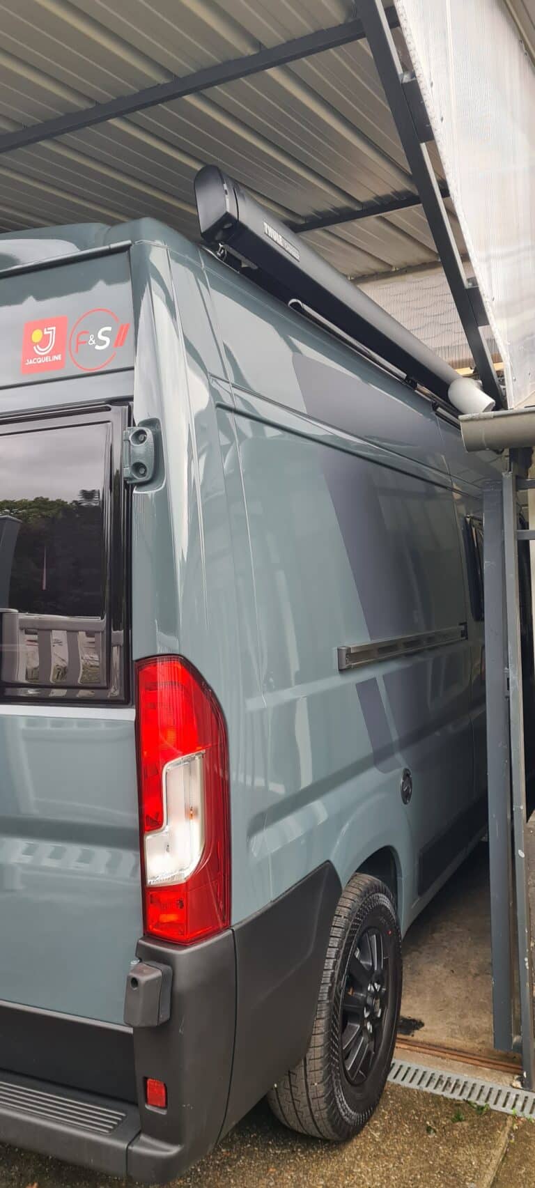 Camionnette grise avec auvent sous abri.