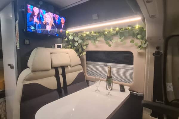 Innenansicht von Campervan mit Tisch und Bildschirm.