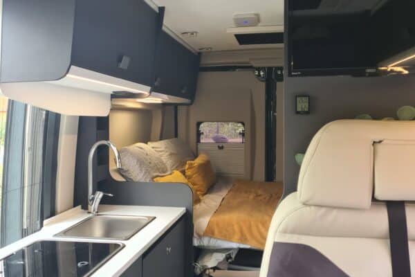 Moderne Inneneinrichtung von Wohnmobil mit Bett und Küche.