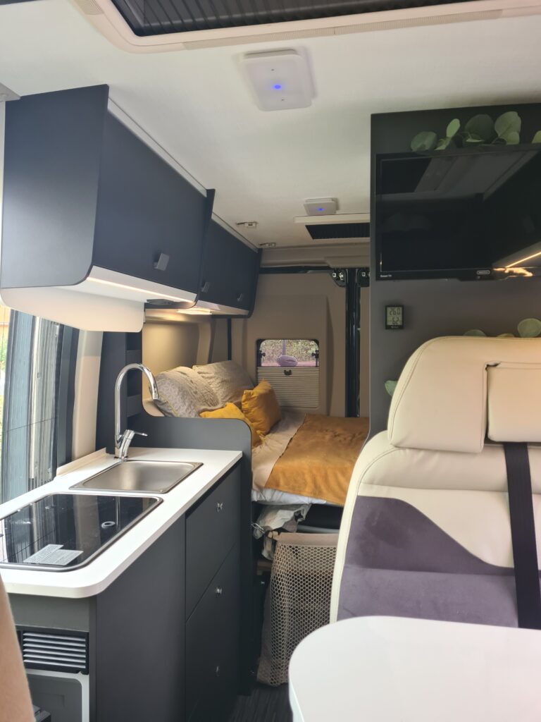 Intérieur moderne de camping-car avec lit et cuisine.
