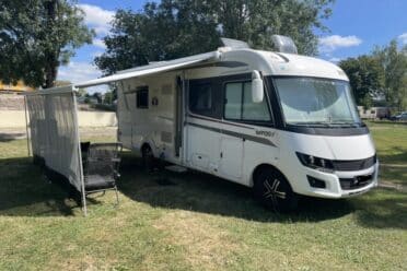 Camping-car stationné sur l'herbe avec auvent.