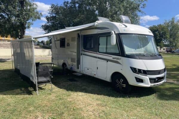 Camping-car stationné sur l'herbe avec auvent.