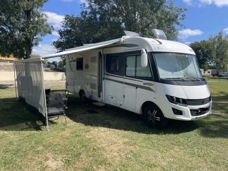 Camping-car stationné sur l'herbe avec auvent.