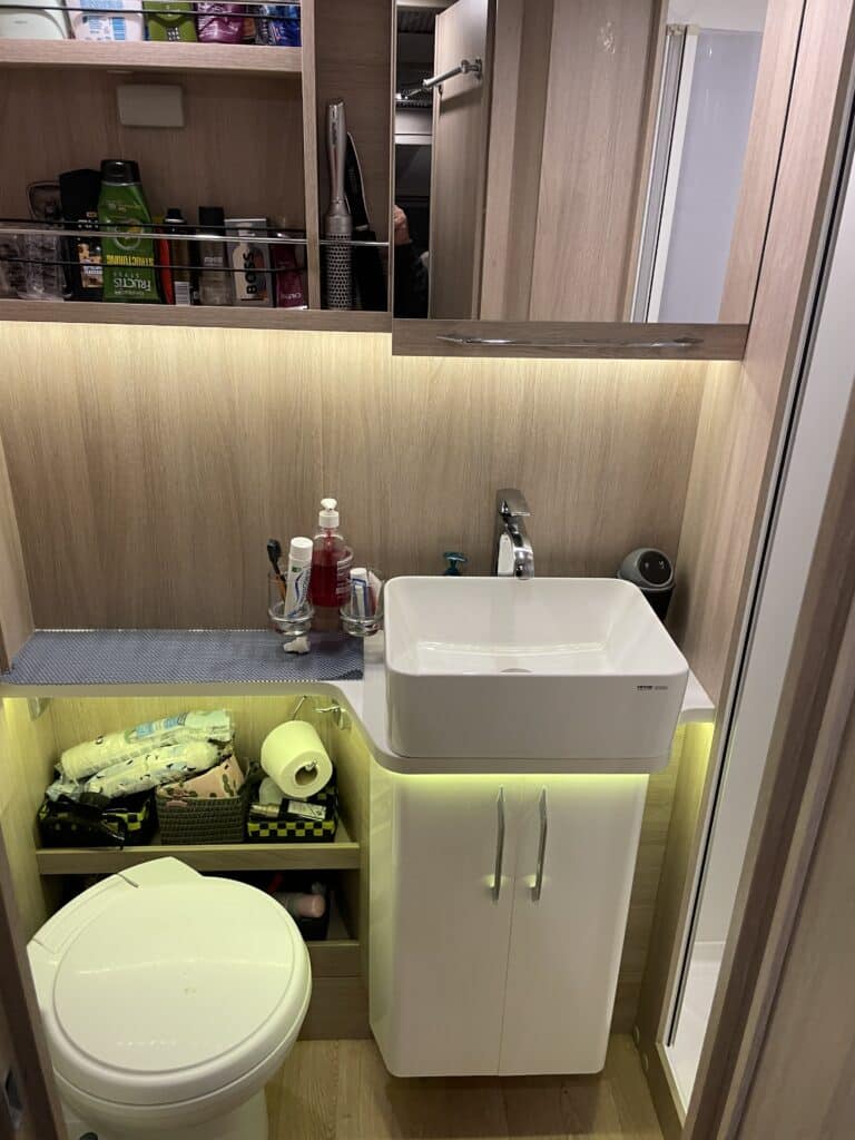 Salle de bain moderne avec lavabo et étagères.