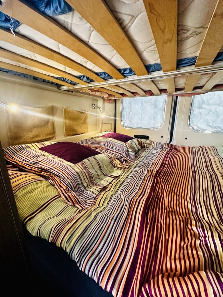 Lit douillet avec couverture rayée dans un camping-car.